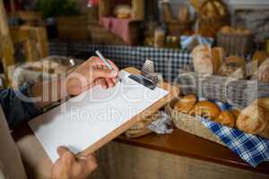 Salesman writing on clipboard at counter