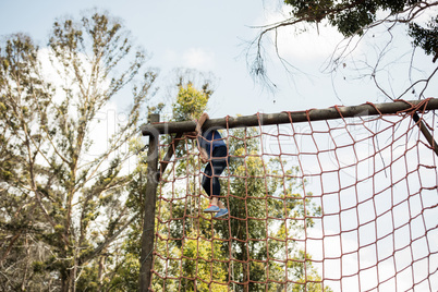 Fit woman climbing a net during obstacle course