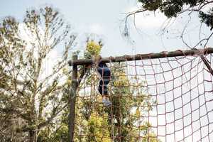 Fit woman climbing a net during obstacle course