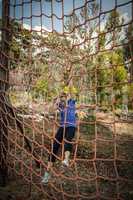 Woman climbing a net during obstacle course