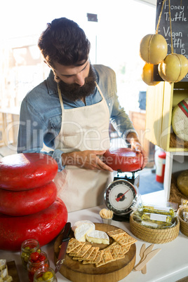 Attentive staff weighing gouda cheese at counter