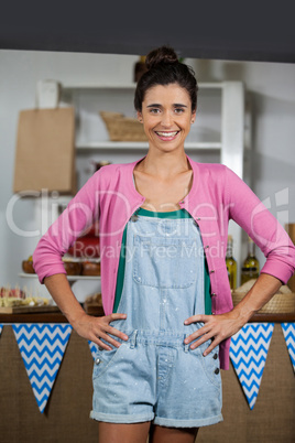 Portrait of smiling female staff standing with hands on hip