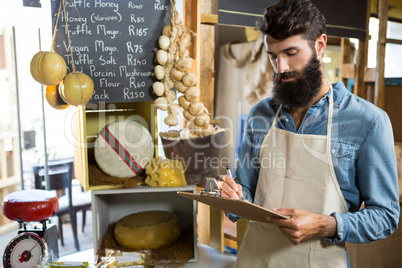 Salesman writing on clipboard at counter in grocery shop