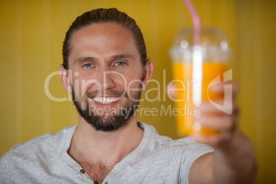 Male staff holding orange juice glass at organic section