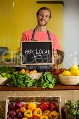 Portrait of male staff holding slate board in organic section