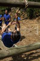 Man crossing the rope during obstacle course while people cheering him