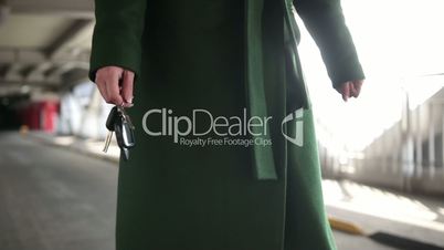 Woman holding modern car key walking to the car
