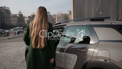 Back view of fashionable woman getting into car