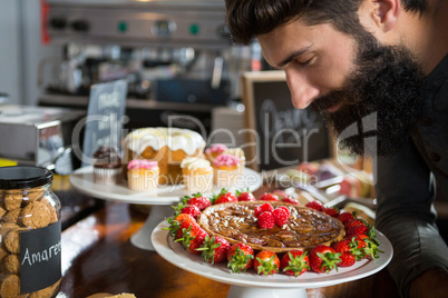 Smiling male customer smelling strawberry pie at counter