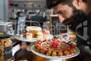 Smiling male customer smelling strawberry pie at counter