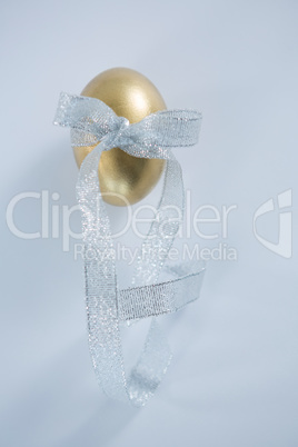 Golden Easter egg tied with ribbon on white background