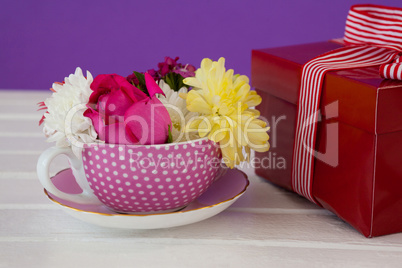 Gift box and fresh flowers on wooden surface