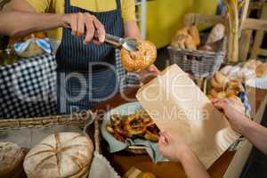 Mid section of staff packing croissant in paper bag at counter
