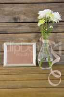 Photo frame and flower vase on wooden surface