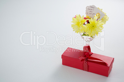 Gift box and flowers in glass with happy mothers day tag