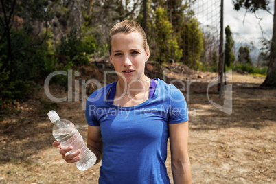 Fit woman holding a water bottle in boot camp