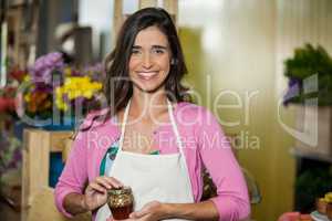 Smiling shop assistant holding a jar of pickle