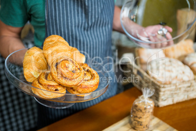 Staff holding tray of croissant at counter