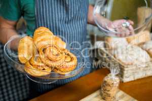 Staff holding tray of croissant at counter