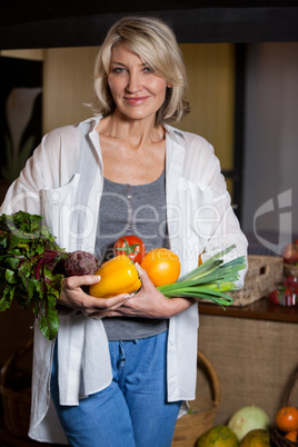 Portrait female costumer holding fresh vegetables and fruits in organic section