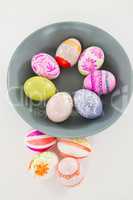 Bowl with painted Easter eggs on white background