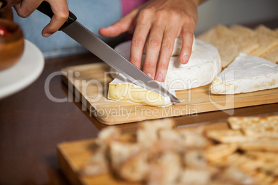 Female staff cutting cheese at counter in market