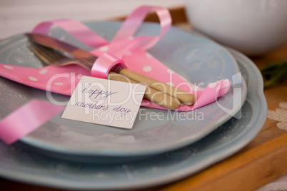 Cutlery, napkin with happy mothers day card on plate