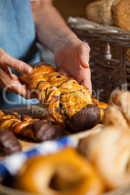 Mid-section of female staff arranging sweet foods