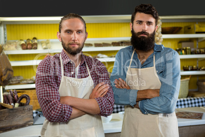 Portrait of smiling two male staff standing with arms crossed