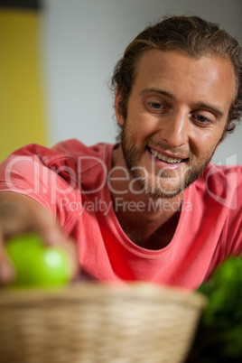 Smiling male staff arranging fruit in organic section