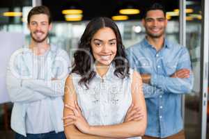 Three smiling executives standing with arms crossed in office