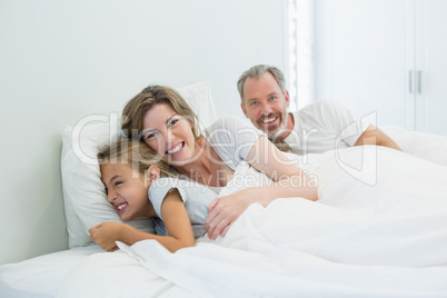 Happy family lying together on bed in bedroom at home