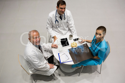 High angle view of doctors and surgeon examining x-ray while having breakfast