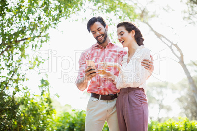 Happy couple laughing while using mobile phone