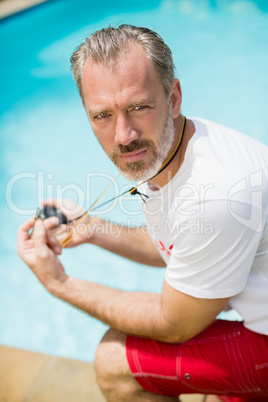 Portrait of swim coach holding stopwatch near poolside