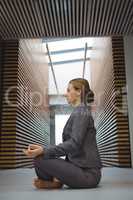 Businesswoman performing yoga in the corridor