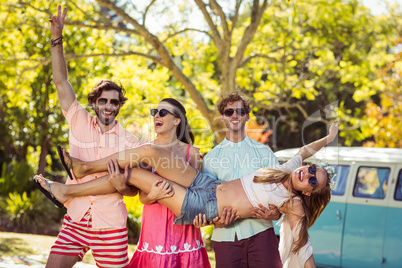 Group of friends carrying a women in park