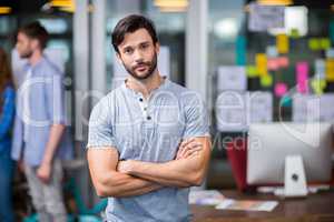 Male executive standing with arms crossed in office