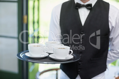 Male waiter holding tray with coffee cups