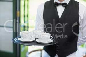 Male waiter holding tray with coffee cups