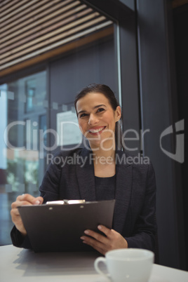 Happy businesswoman writing on clipboard