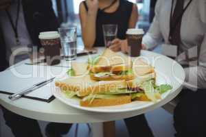 Close-up of breakfast on table with businesspeople in background