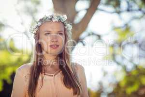 Beautiful woman with flower wreath standing in park