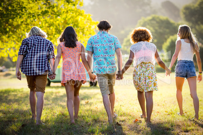 Friends holding hands and walking in park