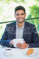 Portrait of happy businessman holding digital tablet