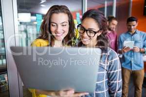 Two smiling female executives using laptop