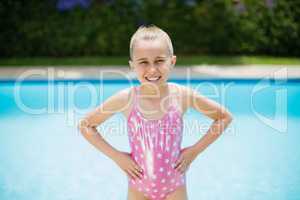 Portrait of girl standing with hands on hip near swimming pool