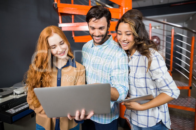 Happy male and female executives using laptop