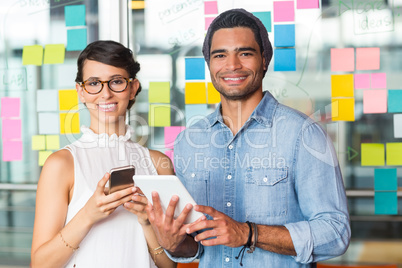 Portrait of executives standing with digital tablet and mobile phone in office