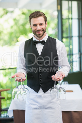 Male waiter holding wine glasses in the restaurant